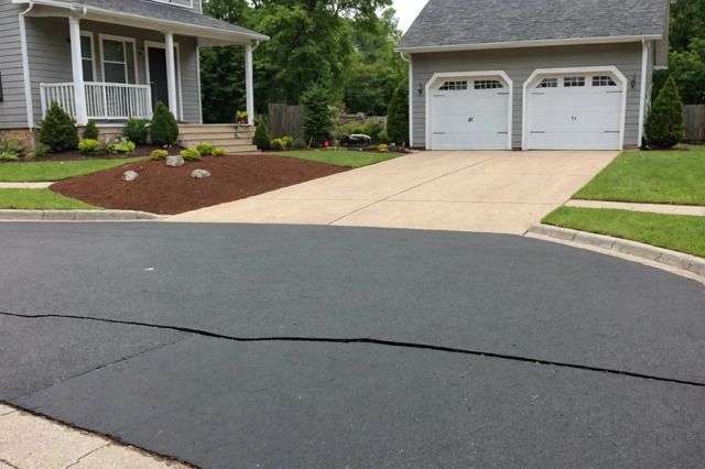 A well-maintained driveway with a split view showing half resurfaced and half fully replaced, surrounded by construction tools and materials